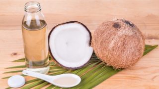 A bottle of coconut oil kept beside a coconut