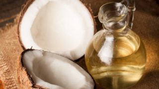 A jar of coconut oil with halved coconuts on a sack