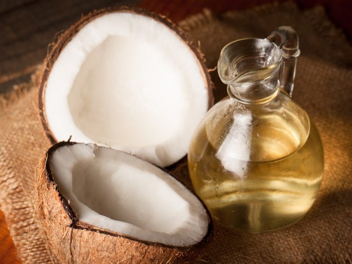 A jar of coconut oil with halved coconuts on a sack