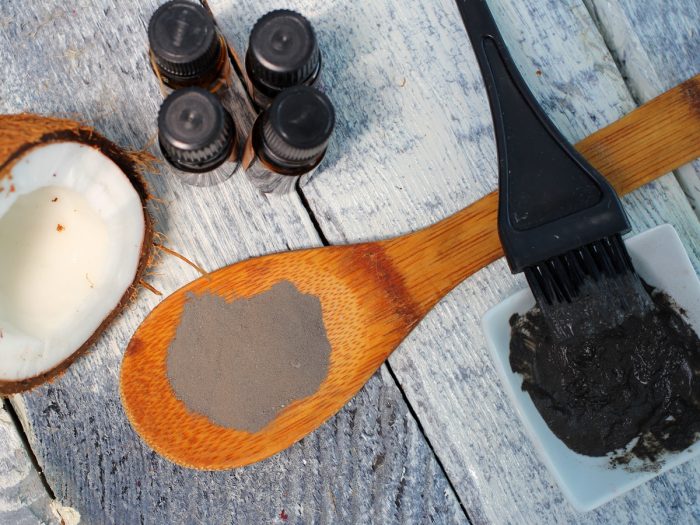 Half a coconut, coconut oil bottles, charcoal powder and paste with a brush