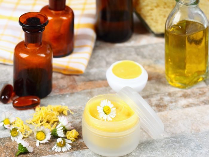 Chamomile flowers, essential oil bottles, pills, and lotion in a small container