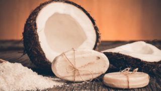Close-up of cracked coconut, coconut soap, and coconut flour on a wooden surface