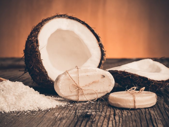 Close-up of cracked coconut, coconut soap, and coconut flour on a wooden surface