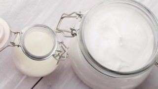 Coconut oil lotion in a large glass jar, next to coconut oil in a small jar