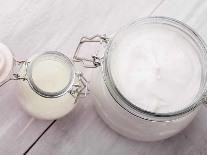 Coconut oil lotion in a large glass jar, next to coconut oil in a small jar