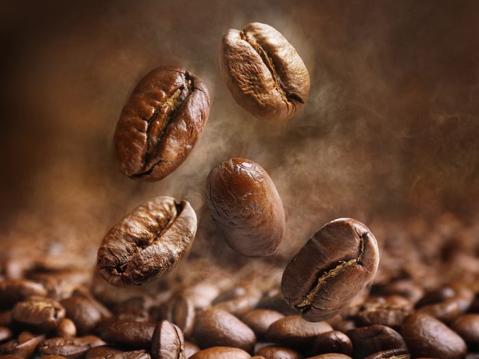 Coffee beans falling on a pile of coffee beans