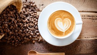 Flatline view of a coffee cup with coffee beans on a wooden background
