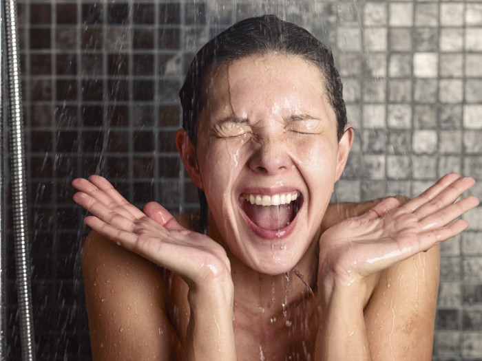 Close up of a woman with eyes closed in happiness under a cold shower