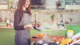 A woman standing in a kitchen cooking something