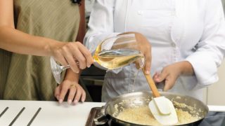 Person pouring wine from a glass in a risotto