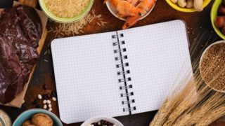 Copper-rich foods such as rice, prawns, groundnuts, barley, pulses, and nutmeg on a table with an open notebook