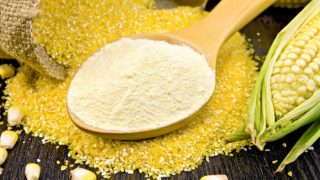 A spoon of cornflour, stone-ground corn grits, corn kernels, and a whole corn