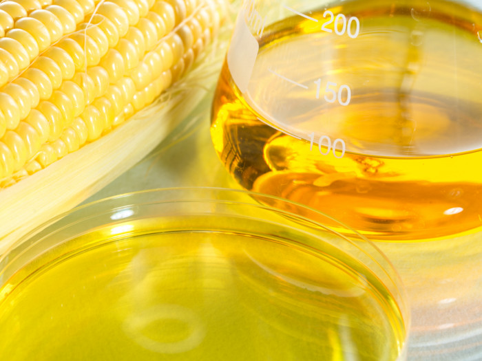 Corn syrup in a measuring jar next to a fresh corn