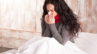 A sick woman blowing her nose.