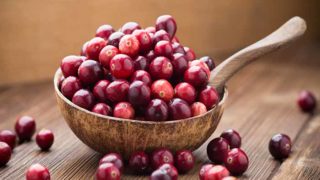 A ladle filled with a few cranberries on the wooden counter