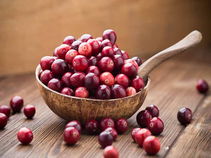 A ladle filled with a few cranberries on the wooden counter