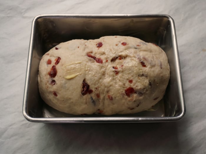 Dough speckled with red berries in a baking pan