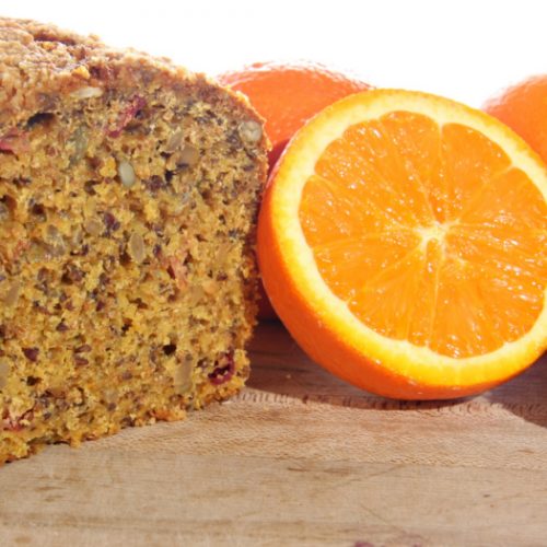 cranberry orange bread next to a halved orange on a counter