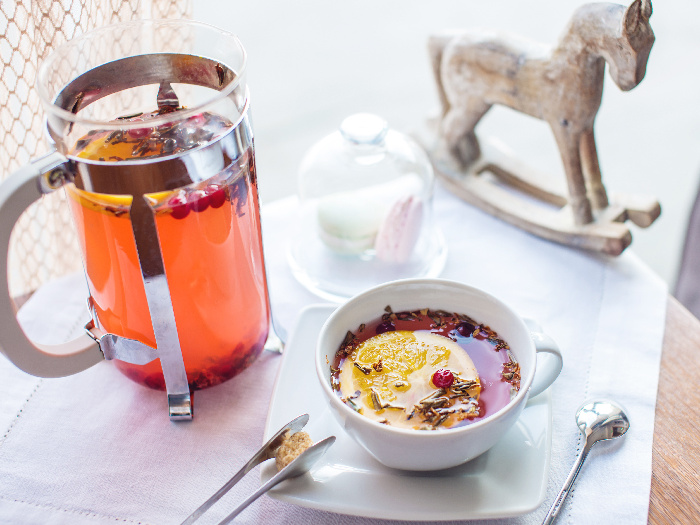 An image of a kettle and a cup of cranberry tea against a white background