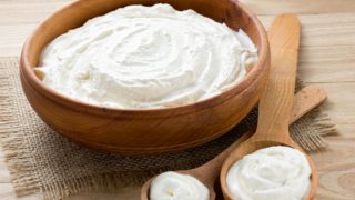 A wooden bowl filled with fresh heavy cream with spoons