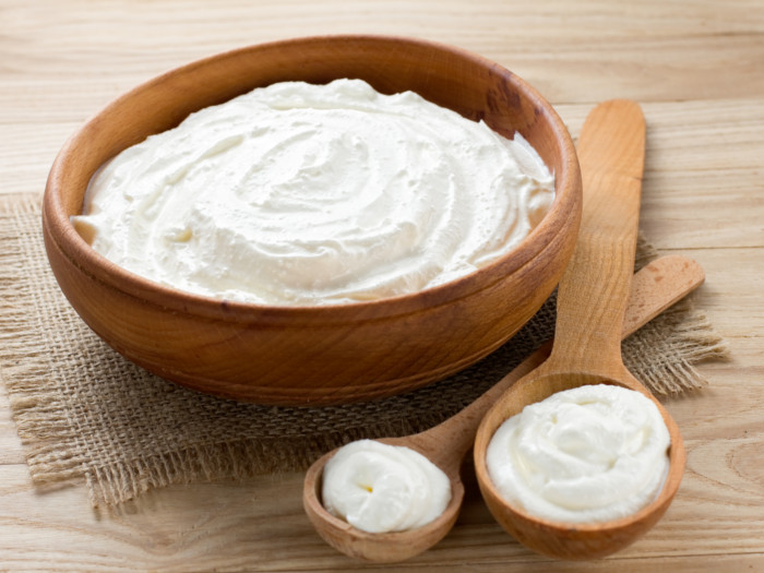 A wooden bowl filled with fresh heavy cream with spoons