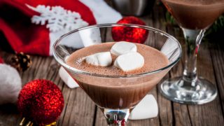 A glass of crème de cacao, garnished with marshmallows, in a festive background