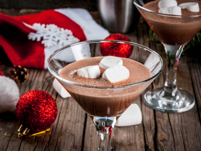 A glass of crème de cacao, garnished with marshmallows, in a festive background