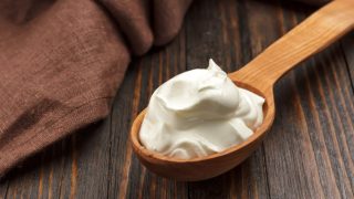 A spoonful of creme fraiche kept atop a wooden table