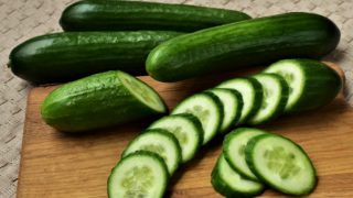 Fresh whole and sliced cucumber on a chopping board