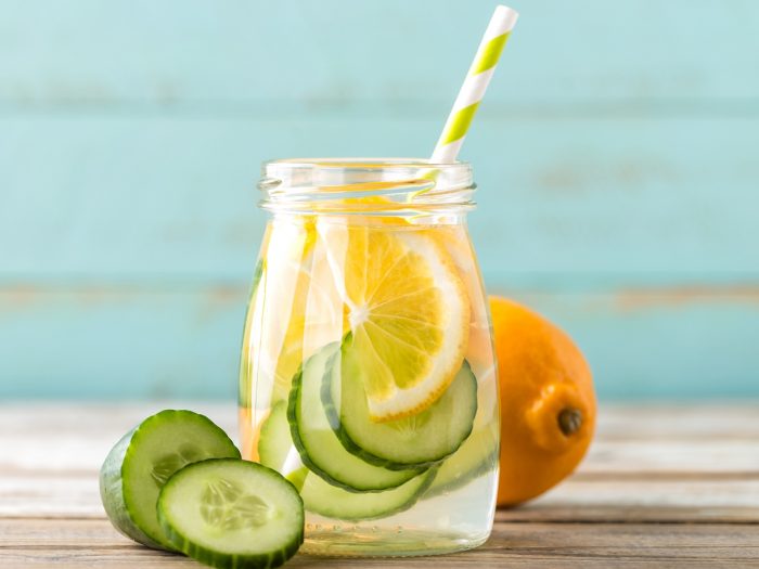 A close-up shot of cucumber lemon water against a light blue background