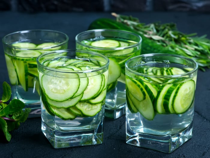 Four glasses filled with cucumber-infused water