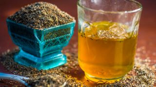 A glass of cumin water and a bowl of cumin seeds