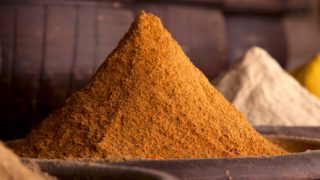 A mountain of freshly grounded curry powder with other spices in the background