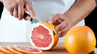 Hands cutting slices of grapefruit