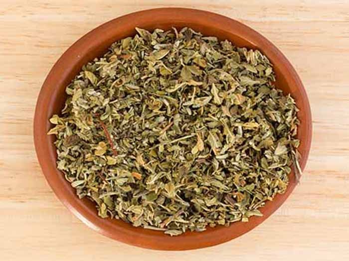 Dried damiana leaves in a ceramic bowl on a wooden counter