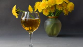A close up picture of a glass of dandelion wine kept atop a table