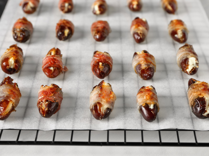 Dried dates wrapped in bacon set on a baking rack