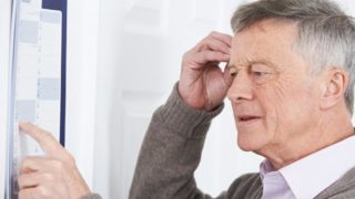 A confused old man suffering from dementia looking at the calendar on the wall