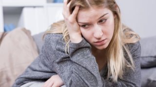 A distressed-looking woman holding her head with one hand.