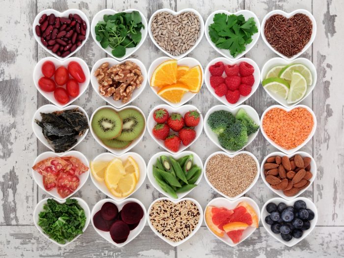 Different bowls neatly aligned on a white background with different detox fruits and vegetables in it