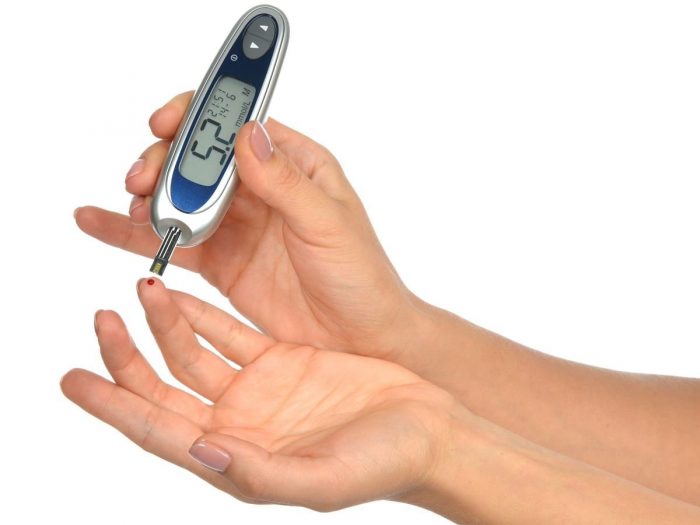 Close up of hands using lancet on a finger to check blood sugar levels