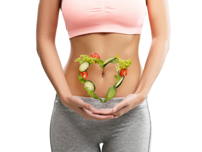 A close-up picture of a woman's stomach with a heart made of vegetables floating in front of it