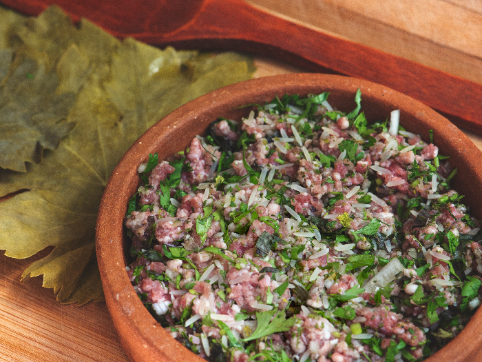 Dolma stuffing in a clay pot besides grape leaves