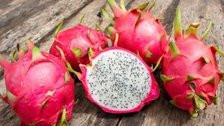 Freshly cut and uncut dragon fruits on a wooden table