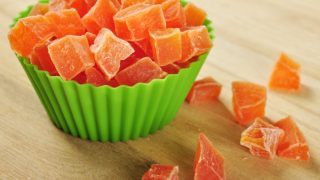 A green bowl filled with cubes of dried papaya