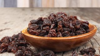 A bowl on raisins on a wooden counter
