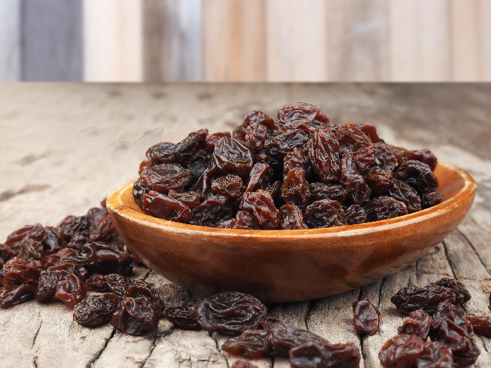 A bowl on raisins on a wooden counter
