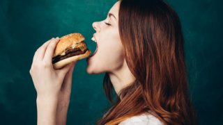 A girl holding a burger and about to eat it