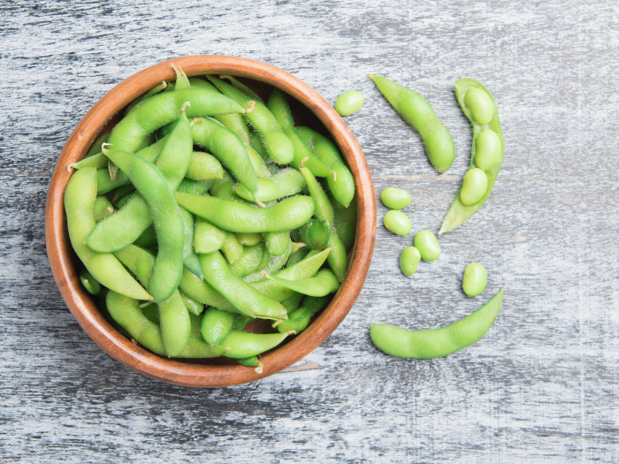A bowl filled with fresh edamame beans on a wooden table
