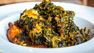 A white plate of Nigerian vegetable Efo Riro soup soup on a white background